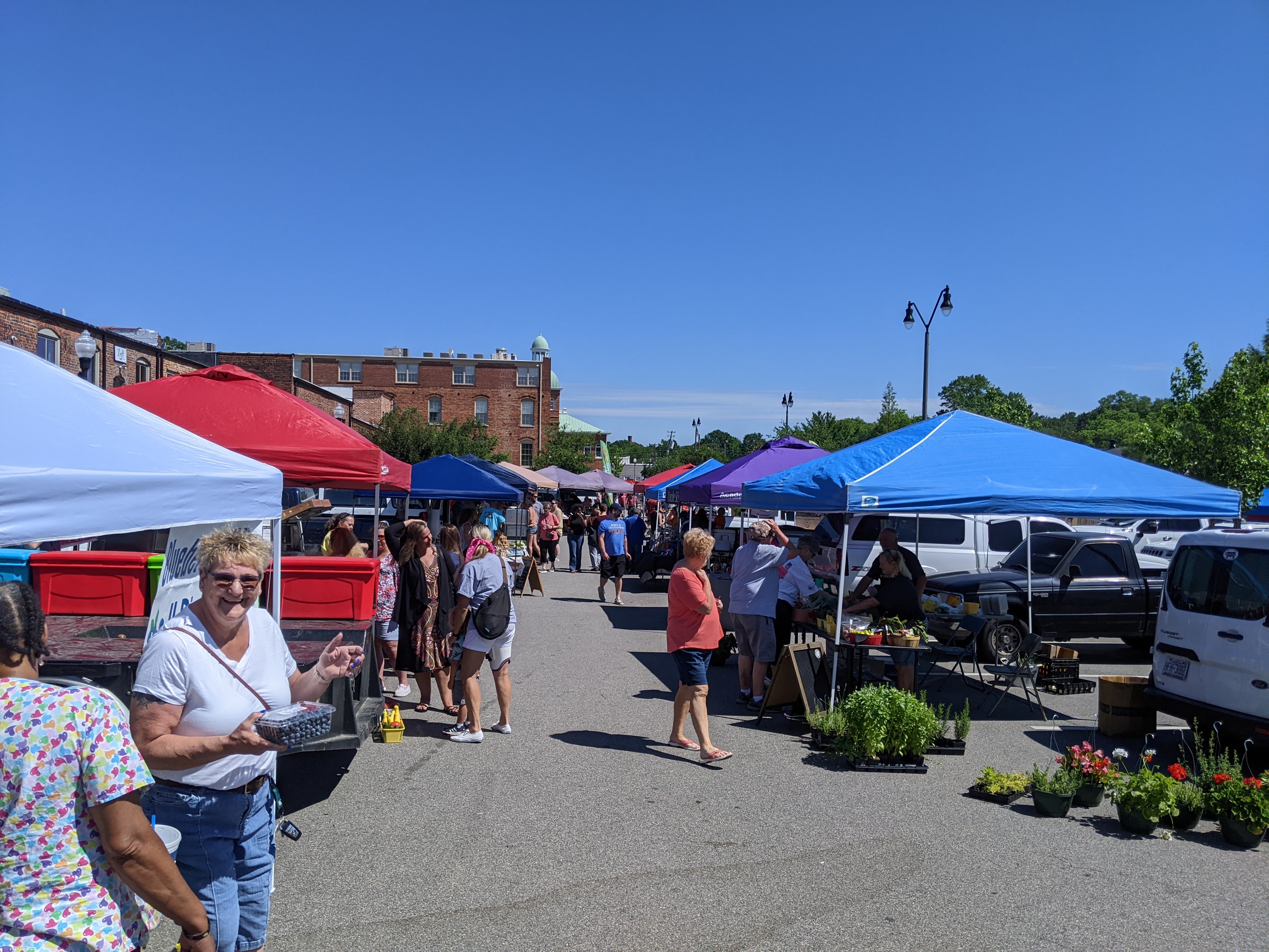 Picture of the Sanford Farmers' Market, with vendors and customers bustling in the market area with local foods and crafts.